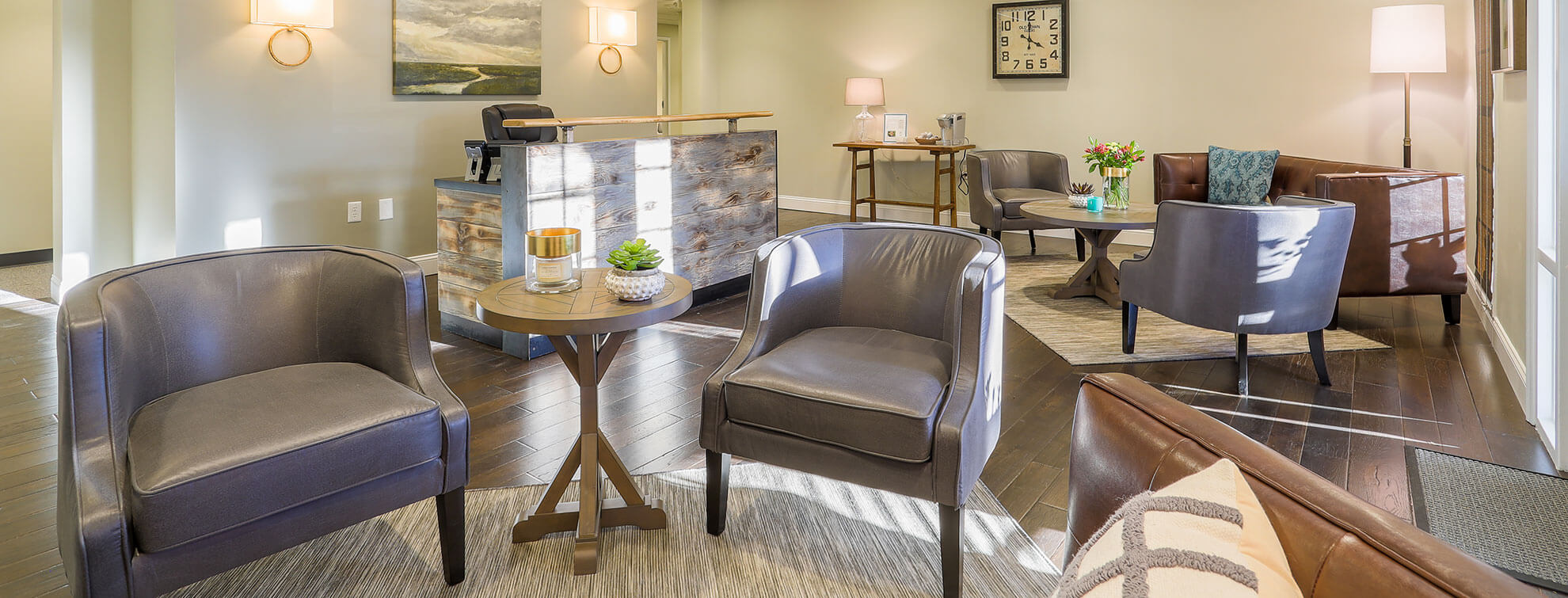 Modern waiting room at The Blanchard Institute in Charlotte with comfortable upholstered chairs in gray and brown tones, arranged around small tables, with warm lighting and a welcoming atmosphere.